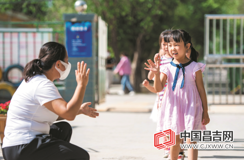 昌吉市三工镇中心幼儿园,入园的小朋友正在和老师打招呼.