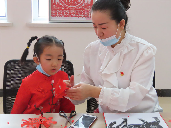 志愿者给小学生教剪纸.jpg 志愿者给小学生教剪纸.jpg